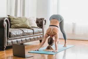 unrecognizable woman in sportswear doing yoga near laptop in apartment